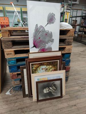 une pile d'œuvres d'art encadrées posées par terre dans un magasin