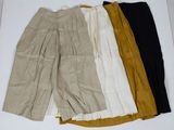 quatre pantalons de couleurs différentes disposés sur une surface blanche