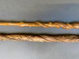 pair of carved wooden walking canes on a gray surface