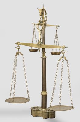 an old brass scale with two chains and a bird on top