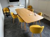 yellow chairs around a wooden table in a room with a flat screen tv on the wall