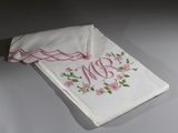 broderie sur un mouchoir blanc orné de fleurs roses et d'un monogramme