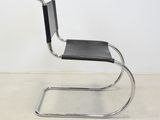 a black leather and chrome chair in the style of person