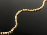 a yellow gold necklace with diamonds on a black surface