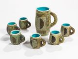 five cups and a jug sitting on a white surface