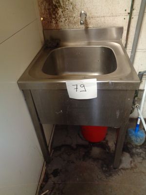 a sink in the corner of a room with a sign on it