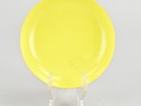 a yellow plate sitting on a clear stand on a white surface