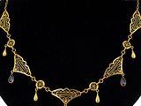 un collier plaqué or orné de pendentifs en verre noir, posé sur un mannequin noir