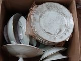 plusieurs assiettes et bols dans une boîte posée sur le sol