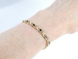someone wearing a gold bracelet with black and white stones on it