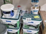 several buckets of paint are stacked on a shelf in a garage