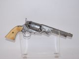 un vieux revolver en argent avec une crosse en bois, posé sur un socle transparent
