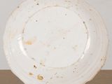 an old white plate sitting on top of a wooden table