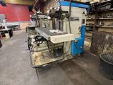 Une grande machine est entreposée dans un entrepôt, à côté d'autres machines.