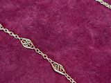 gold plated chain with a heart pendant on a red velvet surface