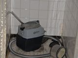 une photo d'une salle de bains sale avec un aspirateur dans un coin