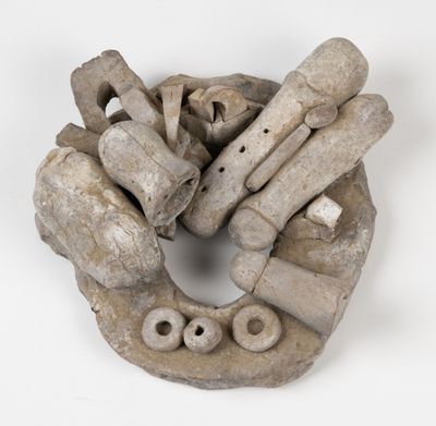 une sculpture en argile et en bois posée sur un fond blanc