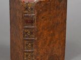 an old book with a brown cover sitting on top of a table