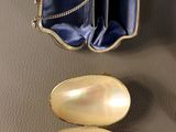 two gold spoons and an empty purse on a table