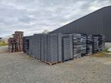 de nombreuses piles de briques empilées sur une palette devant un bâtiment