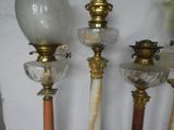 several antique lamps are lined up against a white wall