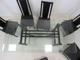 a glass table with four chairs and a laptop on it