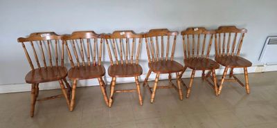 four wooden chairs are lined up against a wall in a room