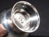 a person holding a silver cup on a black table