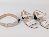 two pairs of white sandals and a belt on a white surface