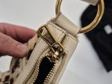 someone is holding a purse with a gold ring on it