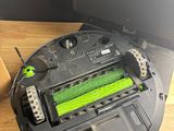 a close up of a robot vacuum on a desk with a monitor