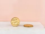 a gold coin sitting on top of a white box next to a pink wall