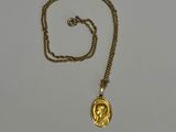 Gros plan sur un collier en or sur lequel se trouve une pièce de monnaie