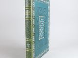 an old book with a blue cover sitting on top of a white table