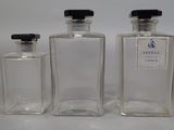 three clear glass bottles with black lids and a black top