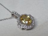 pendentif en saphir jaune et diamants, monté sur une chaîne, sur un fond blanc