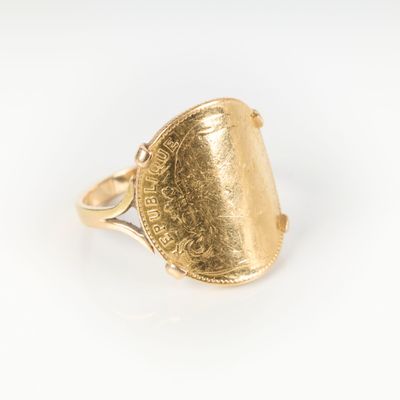 Gros plan sur une bague en or ornée d'une pièce de monnaie