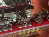 une vitrine remplie de figurines en argent représentant des chevaux et des calèches