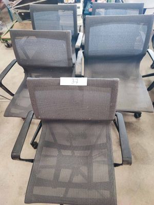 quatre chaises de bureau dans un magasin, avec une étiquette de prix au dos