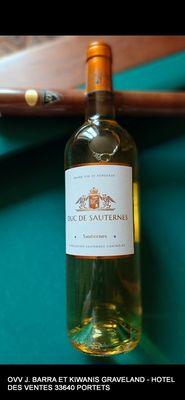 une bouteille de vin posée sur une table de billard, à côté d'un couteau