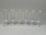 six verres à vin transparents alignés en rang sur une table