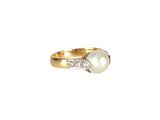 un gros plan d'une bague en or sertie d'une perle blanche et de diamants