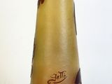 un vase marron surmonté d'un couvercle doré, posé sur une surface blanche