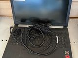 un ordinateur portable posé sur un bureau, avec son chargeur