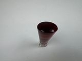 a small wine glass sitting on a white surface