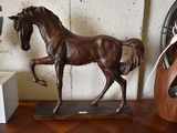 une statue de cheval posée sur une table, à côté d'un vase