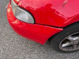 a close up of a red car that has a dent in it