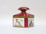 a small pink and gold box with a bird on it