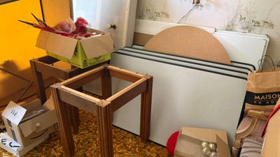 une pile de cartons et une table dans un coin de la pièce