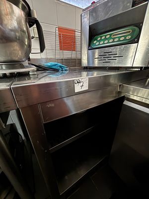 plan de travail en acier inoxydable avec four et lave-vaisselle dans une cuisine professionnelle